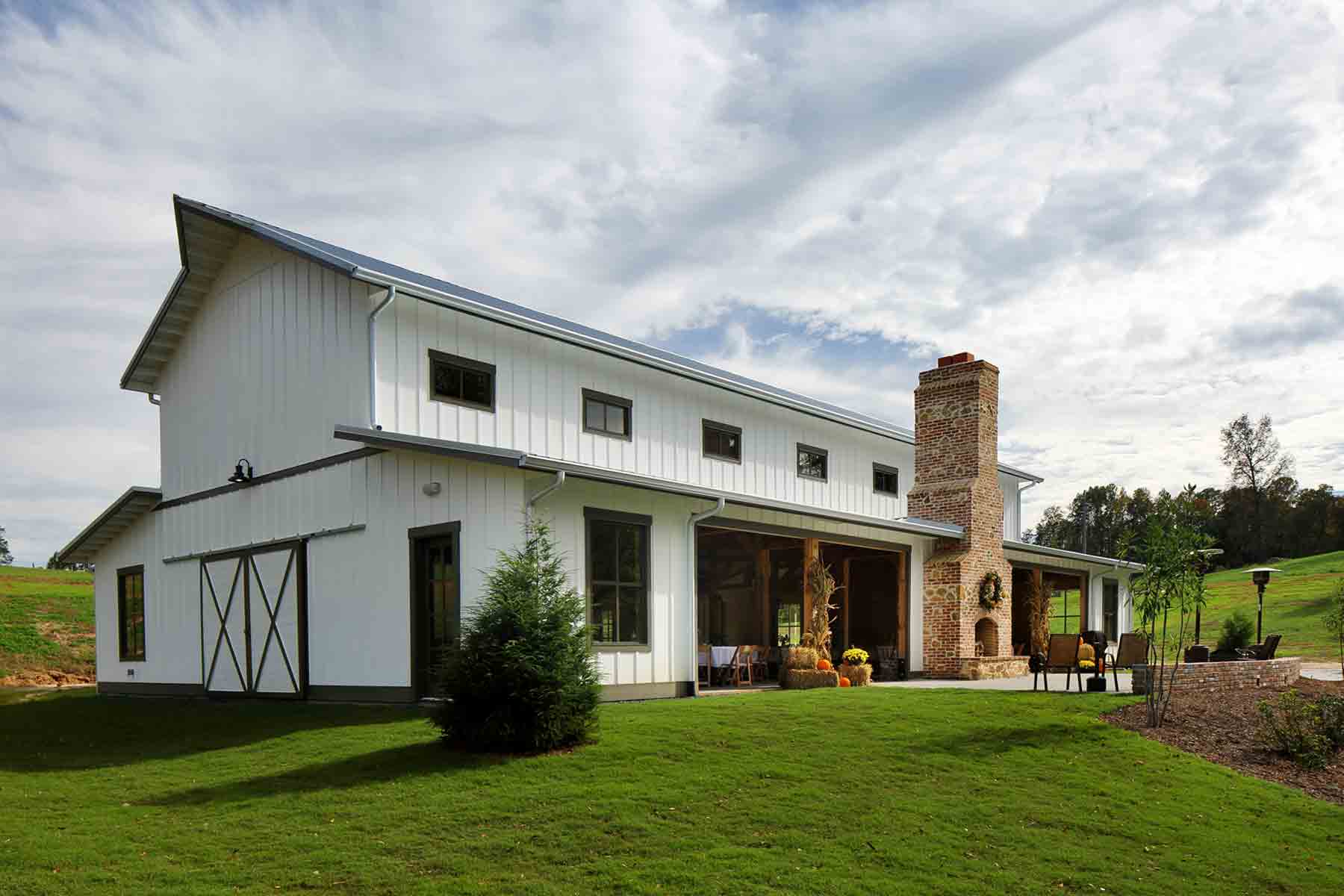 A modern barndominium house with an outdoor patio.