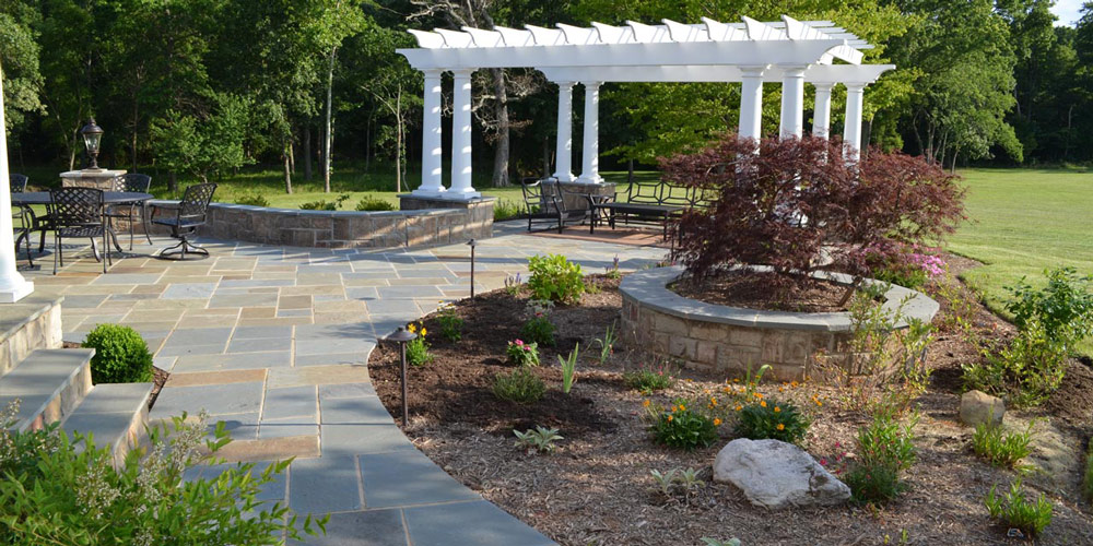 Bluestone patio pavers with surrounding landscaping and arbor