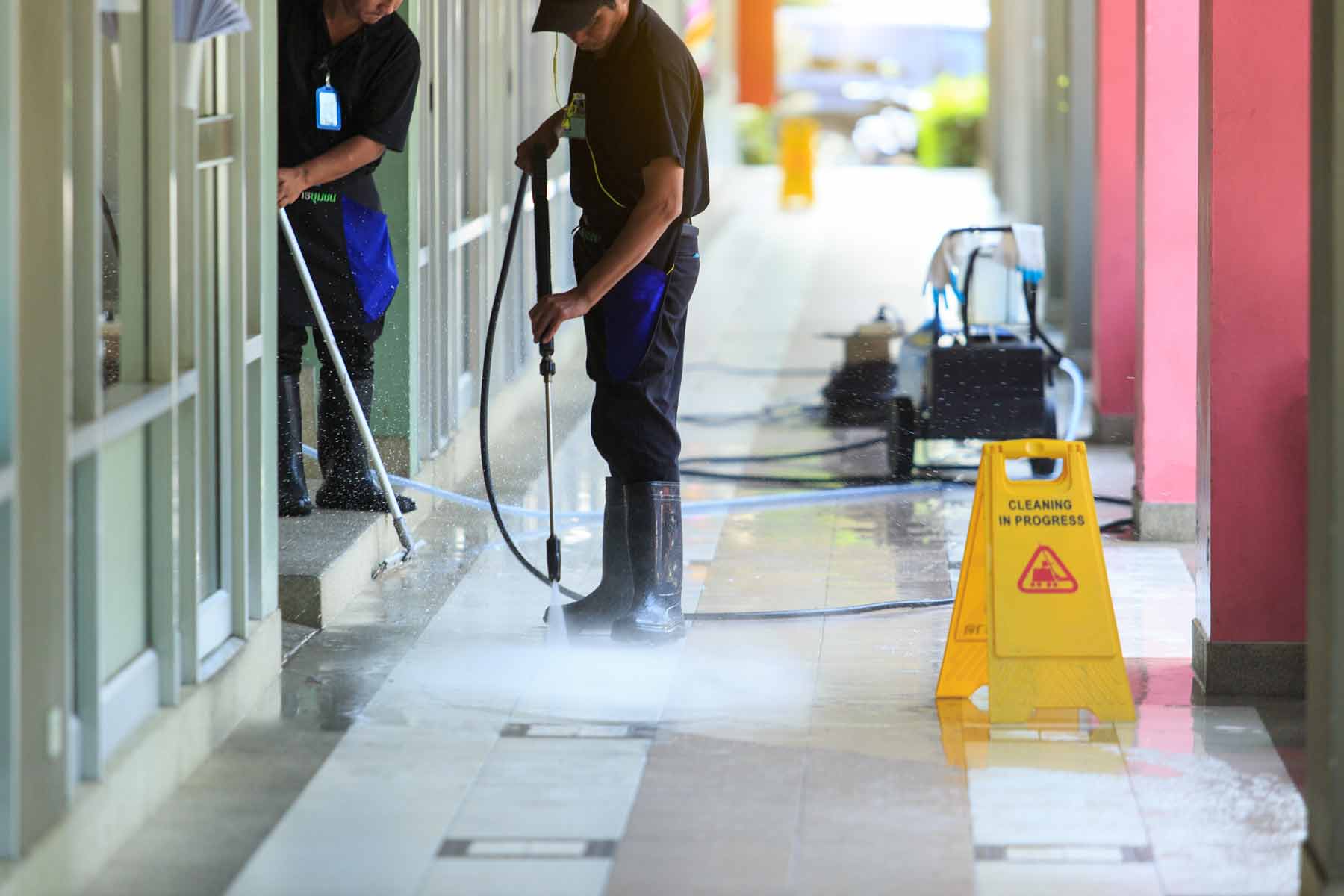Workers using pressure washers to clean outside a commercial business entrance. Workers using pressure washers to clean outside a commercial business entrance.