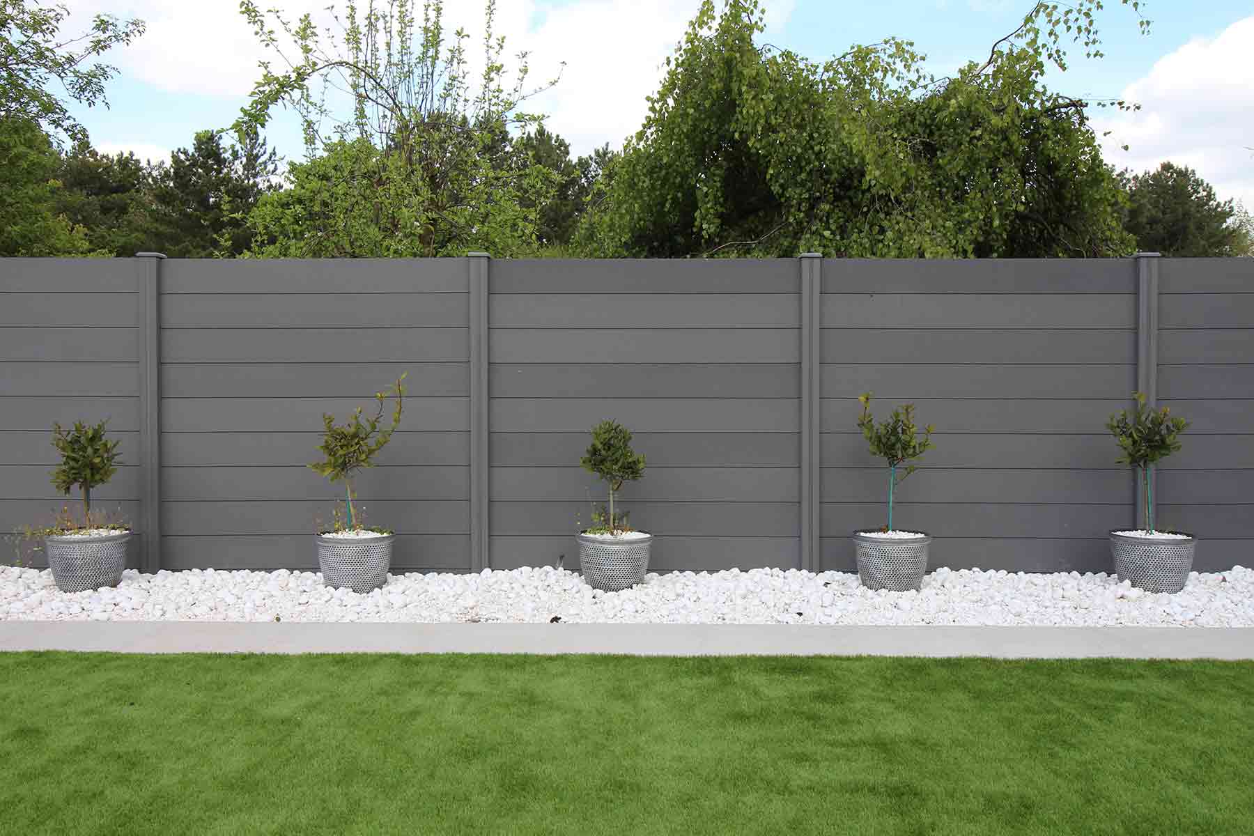 Modern backyard with gray composite fence and decorative potted plants