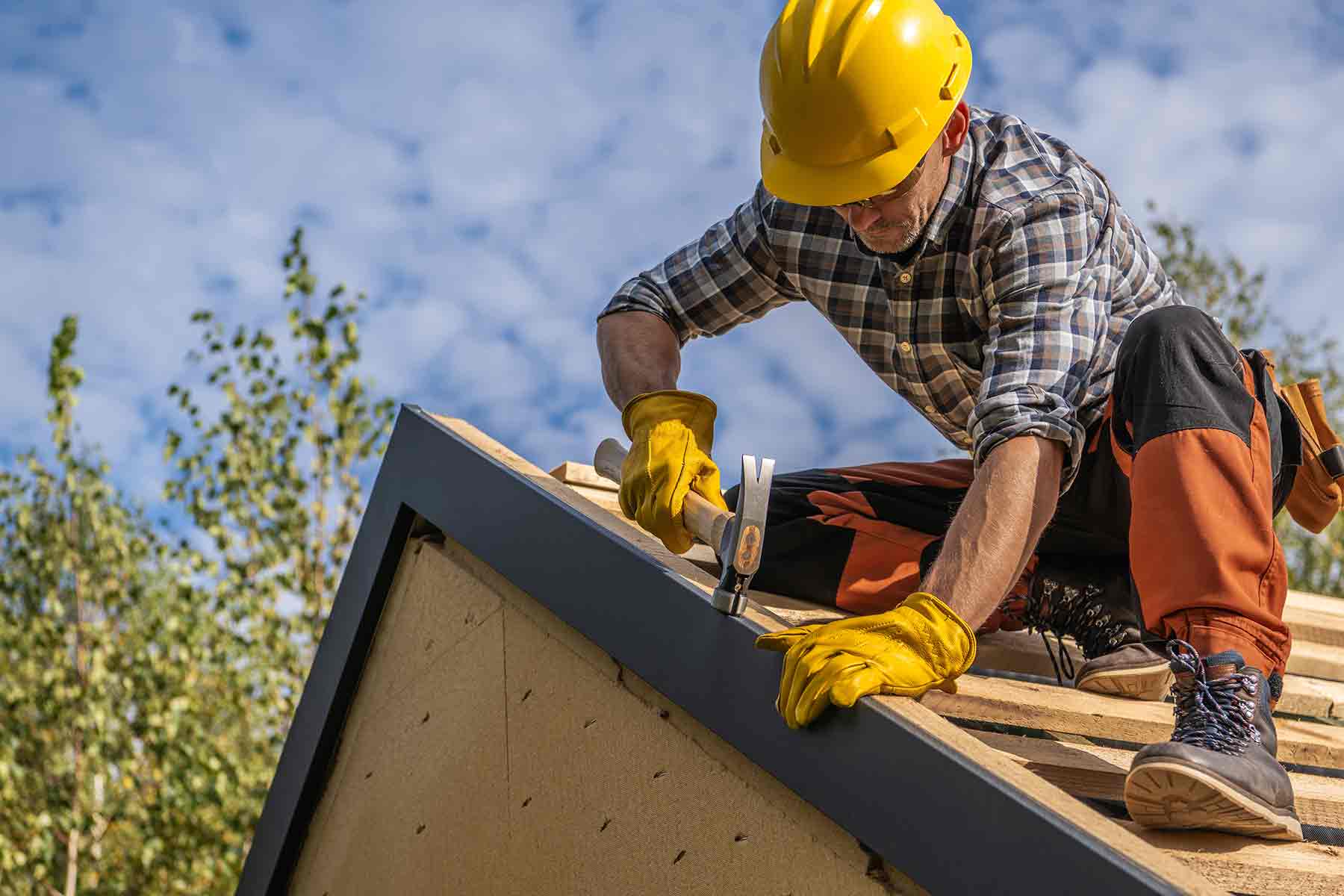 A roofing contractor installing roof edge trim on a new house construction