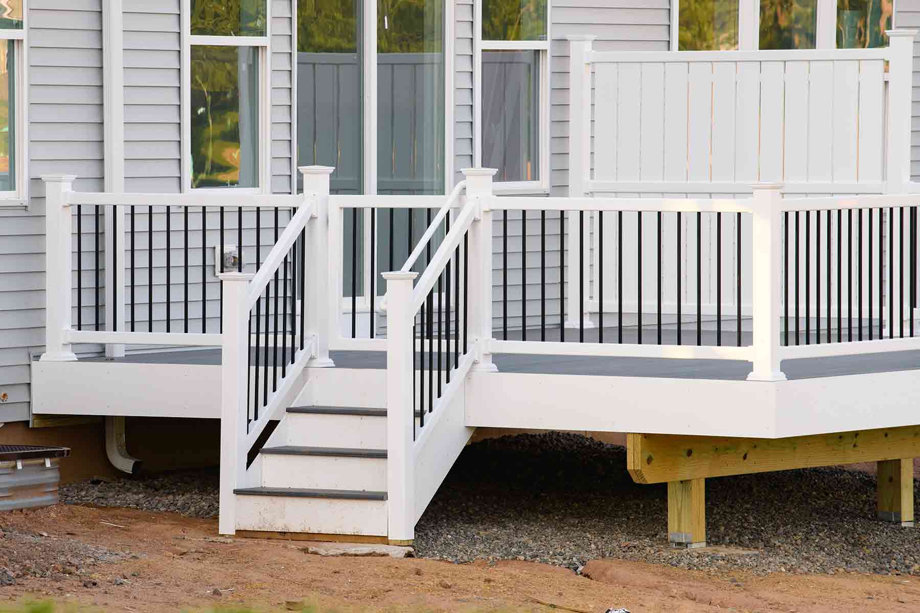 Newly built white vinyl deck stairs with railing at the back of a house Newly built white vinyl deck stairs with railing at the back of a house