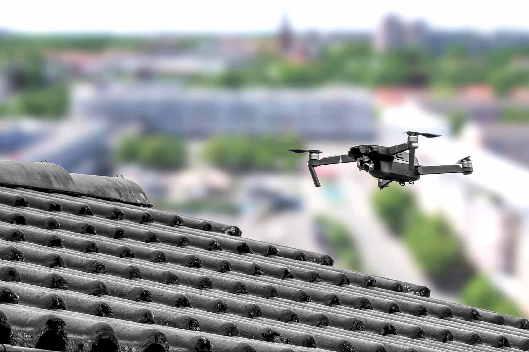 A drone conducting a roof inspection on a residential house