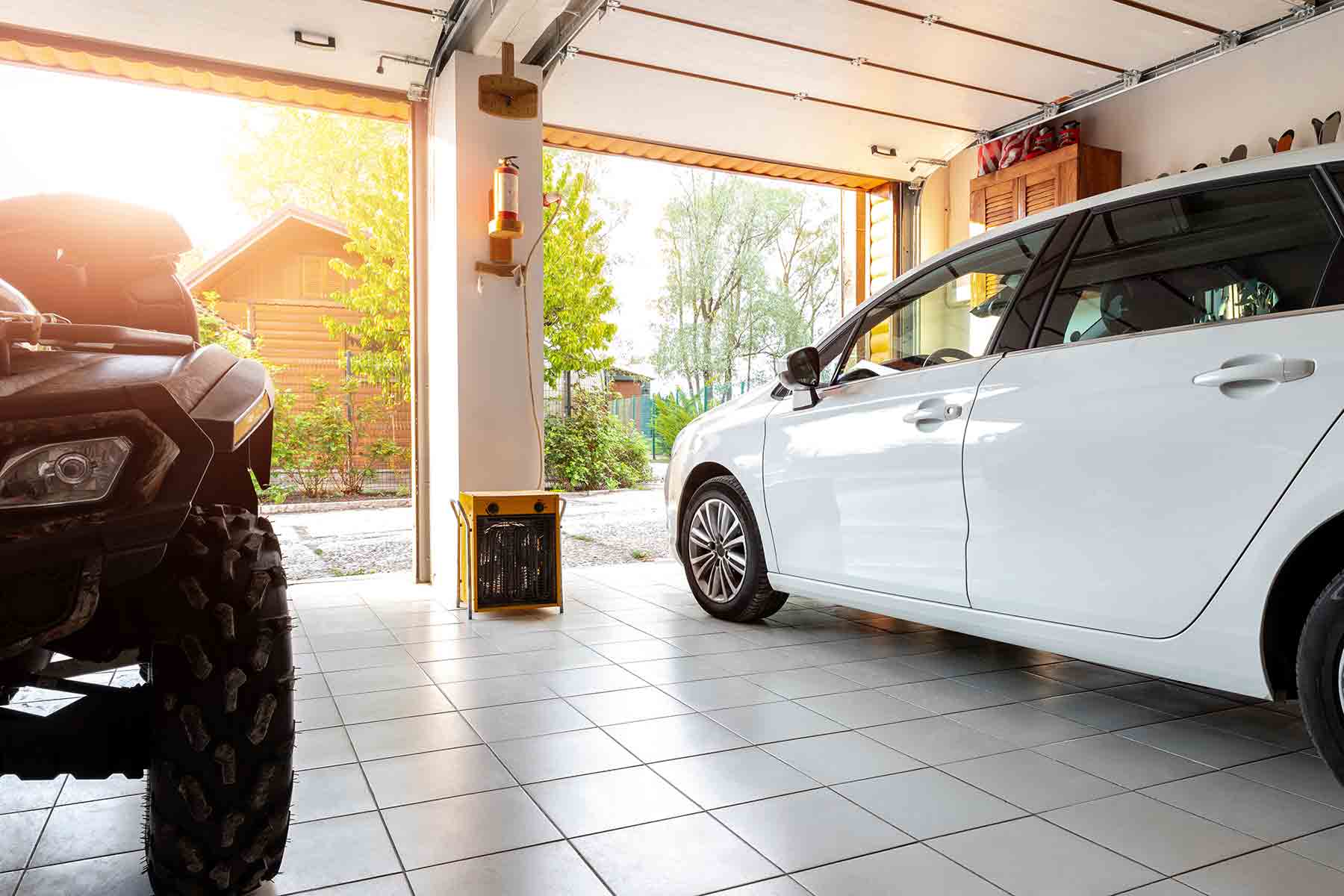 Spacious interior view of a modern two-car garage with open overhead doors and park vehicles Spacious interior view of a modern two-car garage with open overhead doors and park vehicles