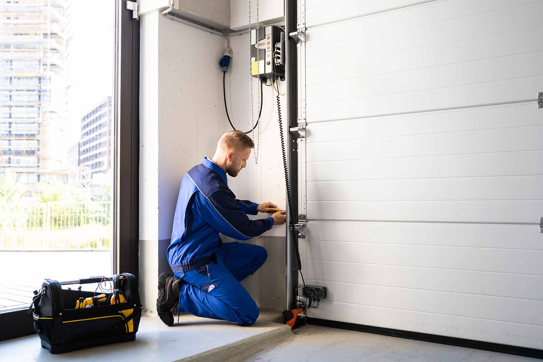 Door technician performing a tune up and maintenance check on a white garage door