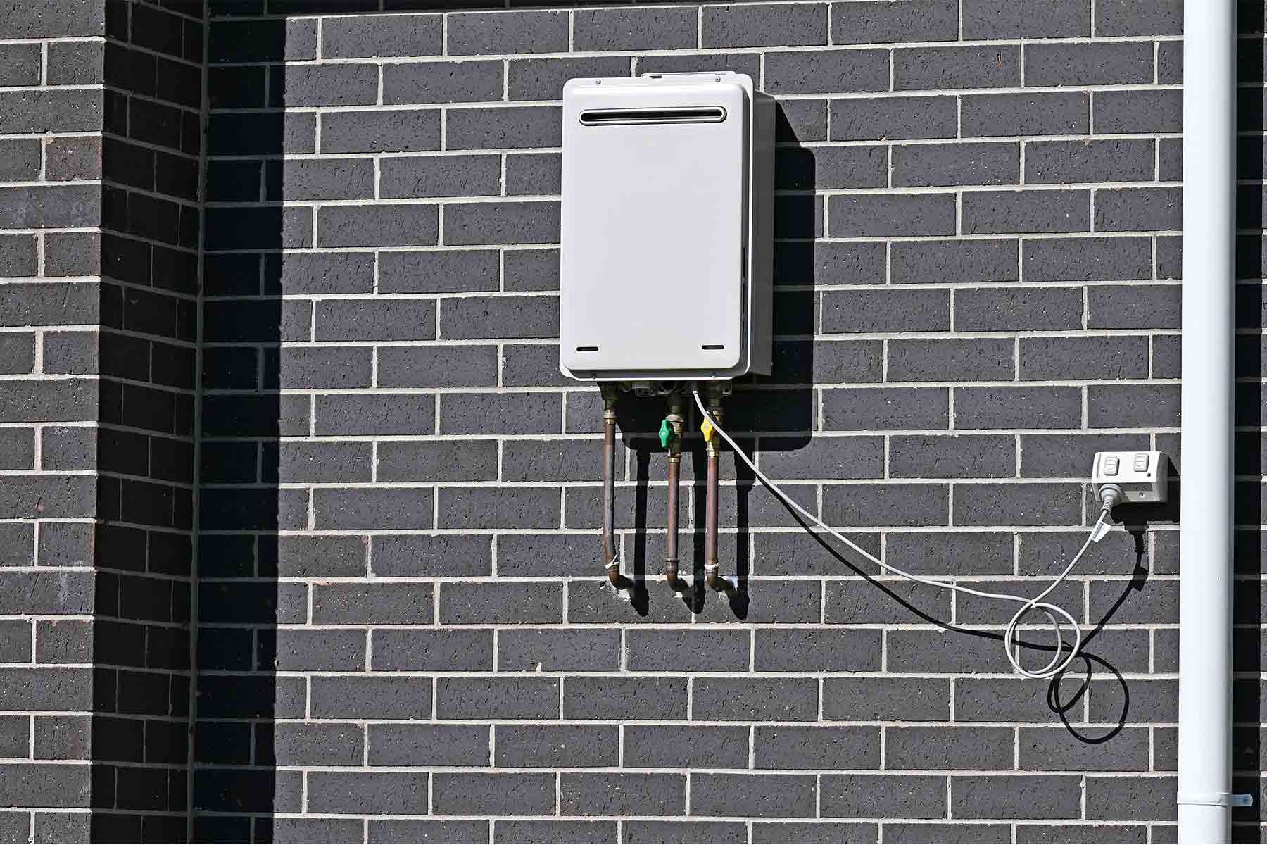 Gas tankless water heater mounted on exterior wall Gas tankless water heater mounted on exterior wall