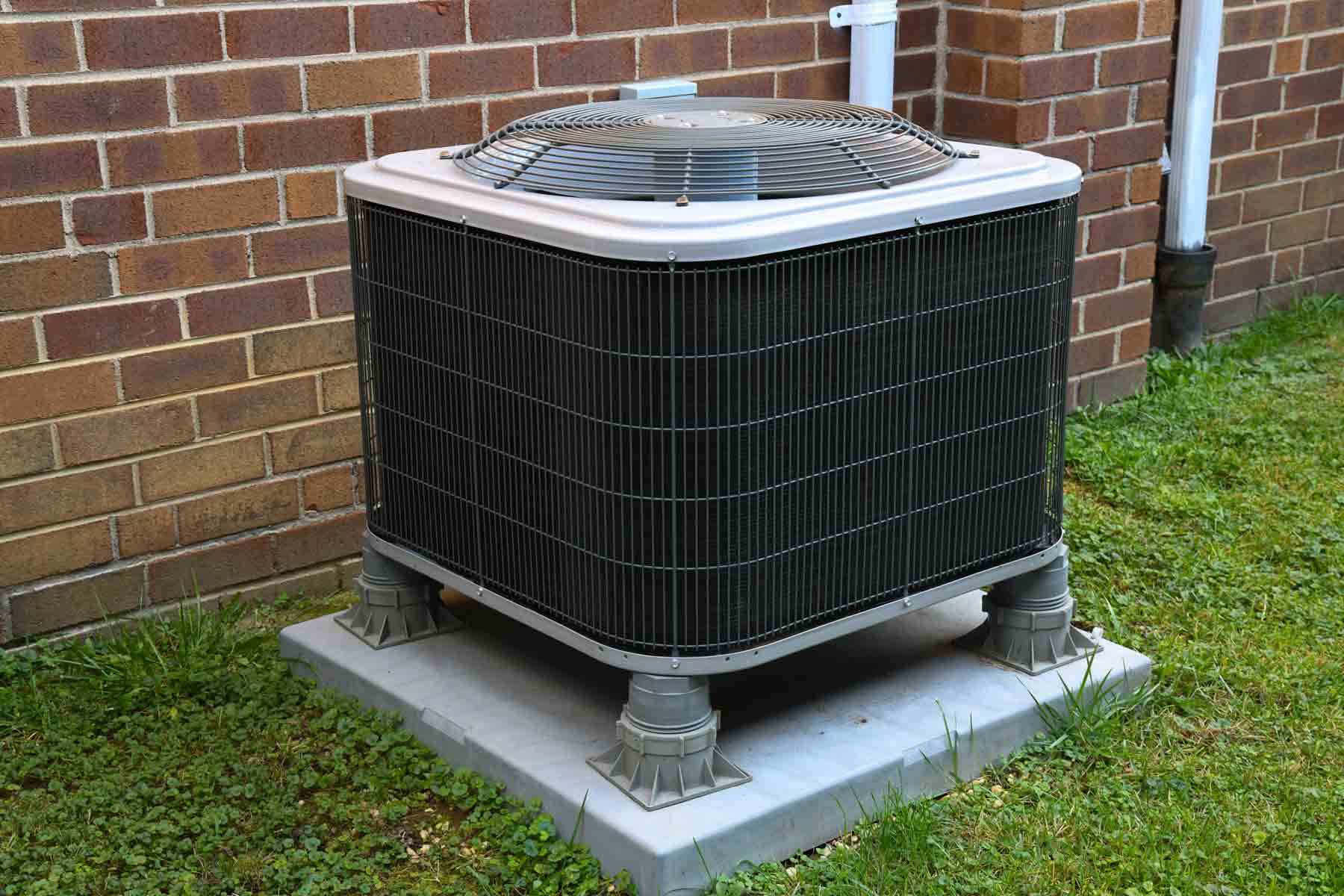HVAC outdoor condenser unit elevated on a concrete pad next to a residential home HVAC outdoor condenser unit elevated on a concrete pad next to a residential home