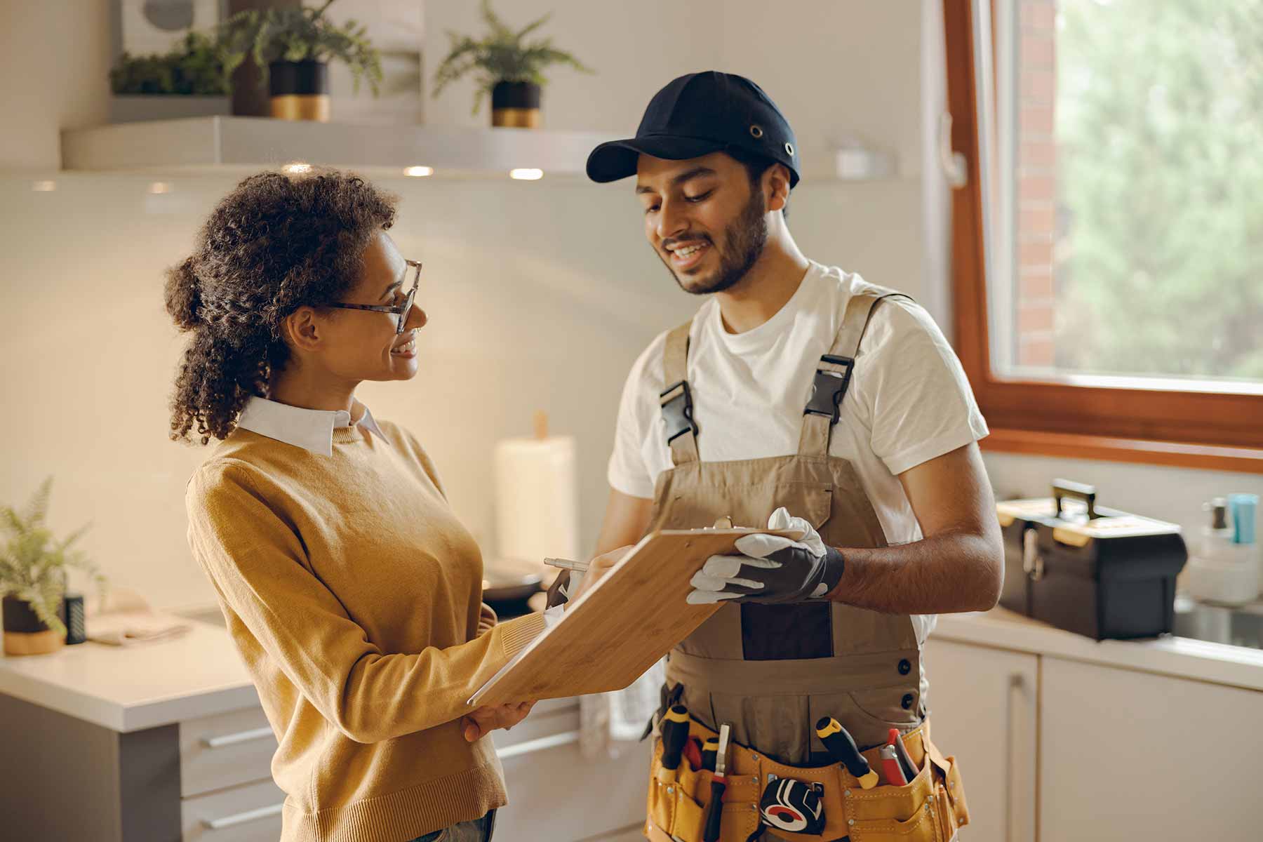 A professional plumber discusses his services with a client as she signs the service form A professional plumber discusses his services with a client as she signs the service form