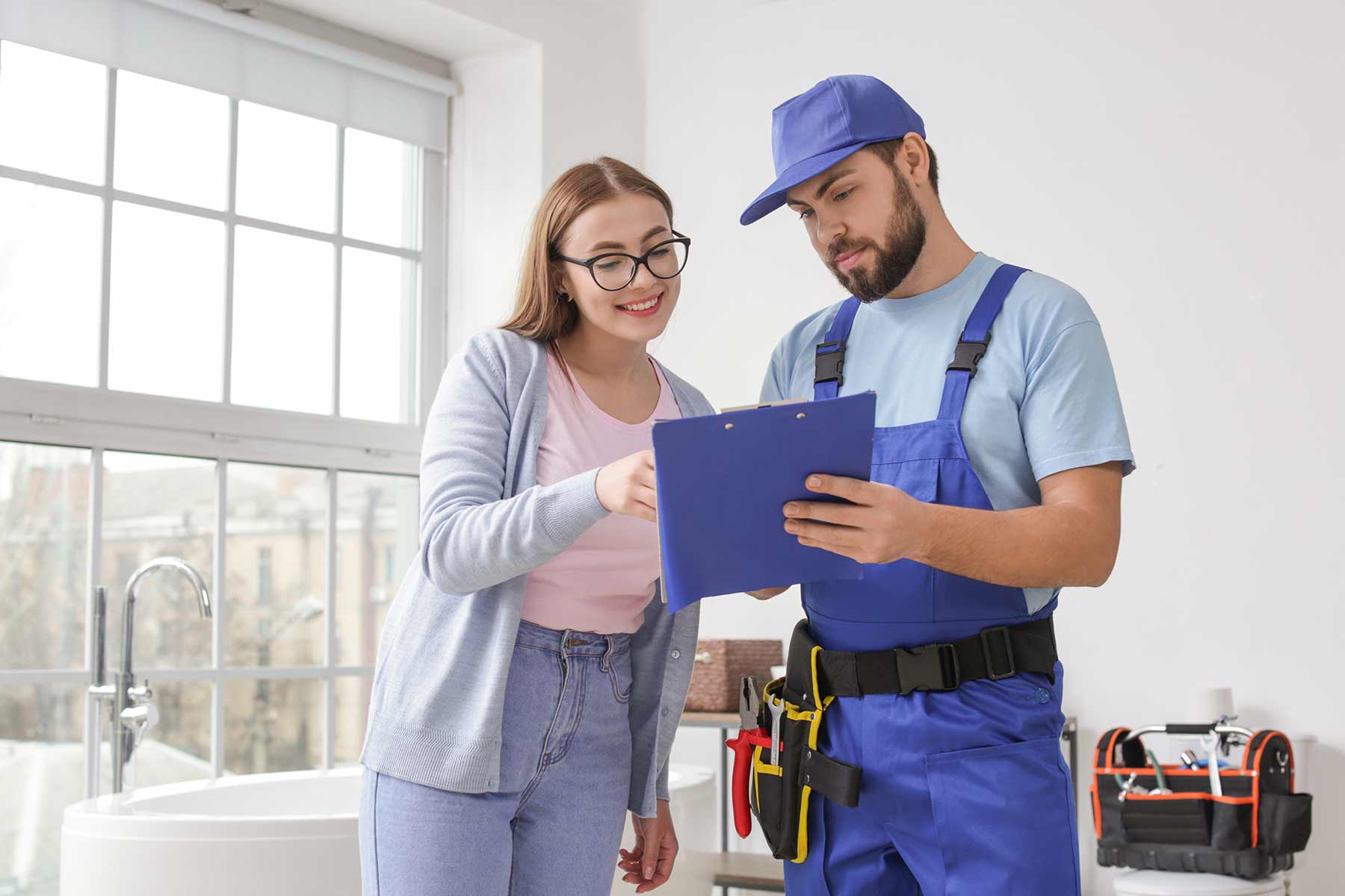 A professional plumber discussing service details with a client during a home visit A professional plumber discussing service details with a client during a home visit