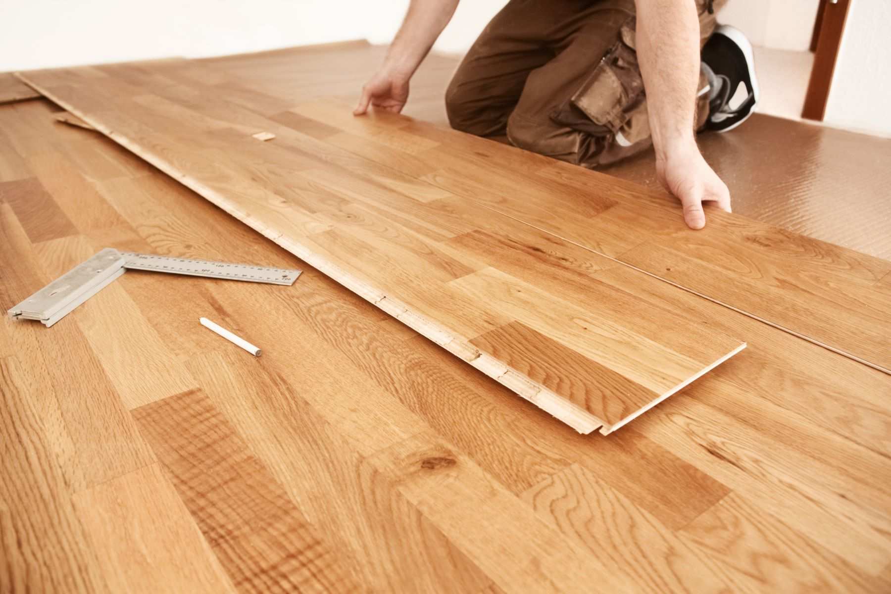A professional installing engineered hardwood flooring in a room A professional installing engineered hardwood flooring in a room