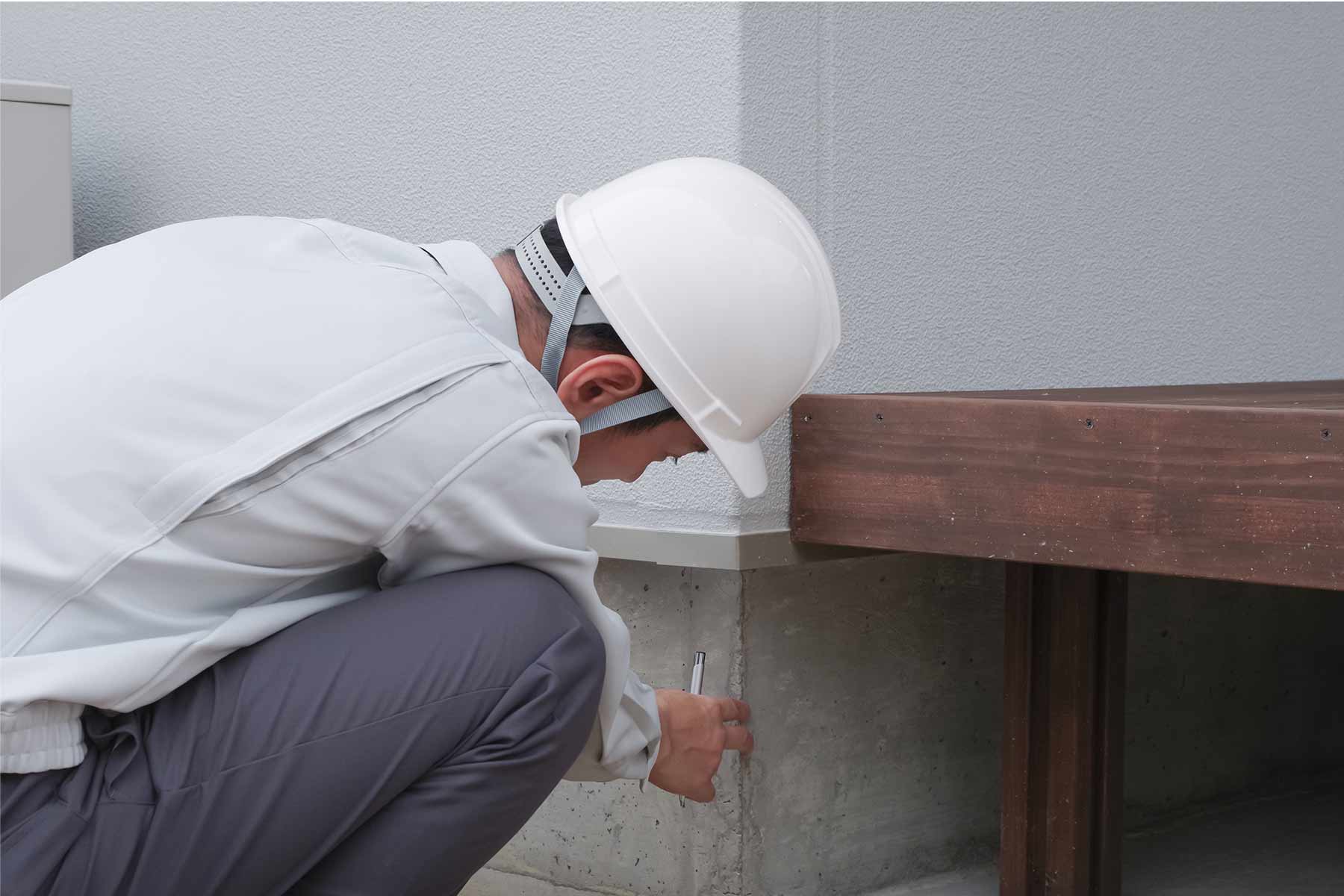 An inspector checking a house foundation for signs of sinking damage