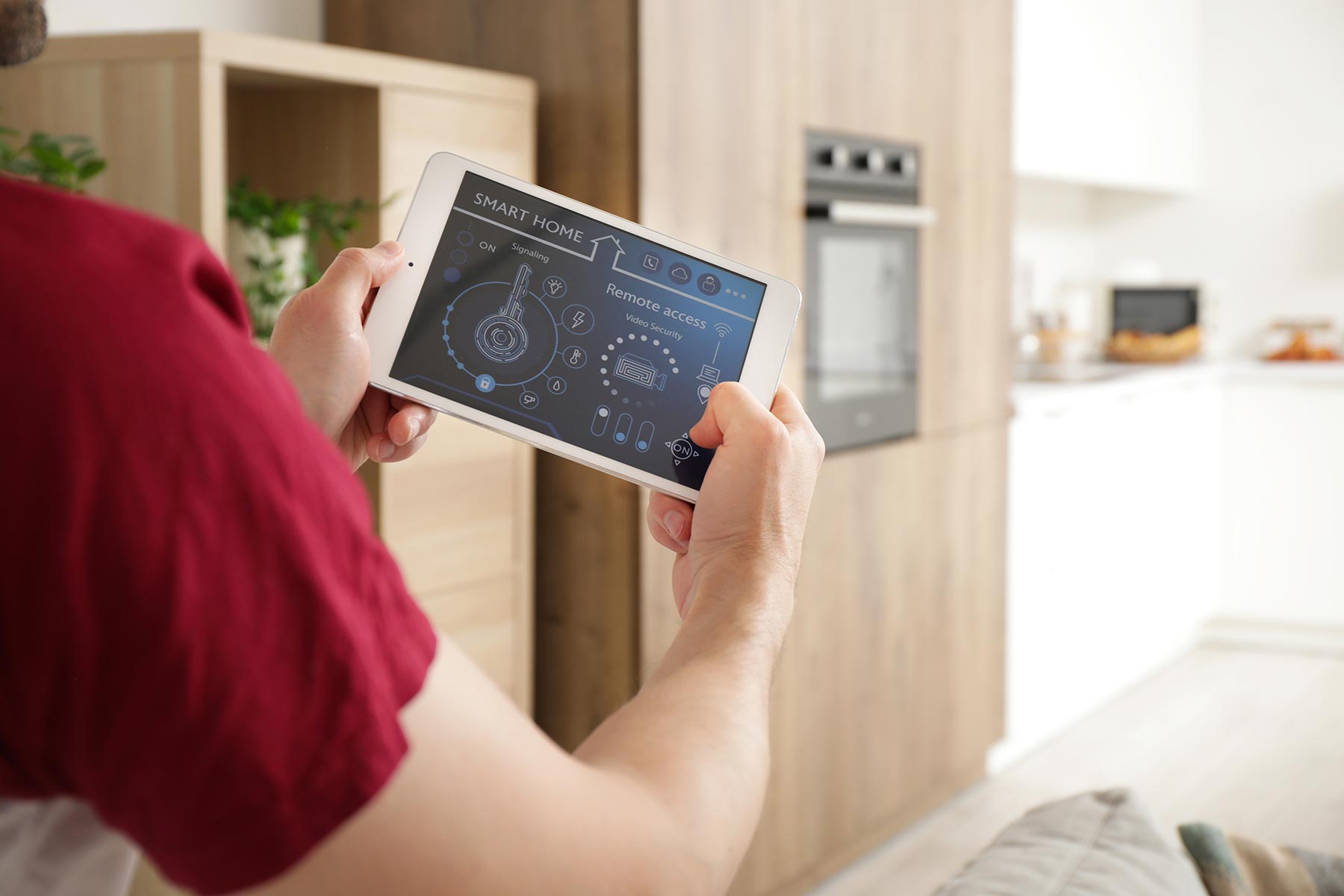 A man holding a smart home control panel to adjust settings in a modern kitchen