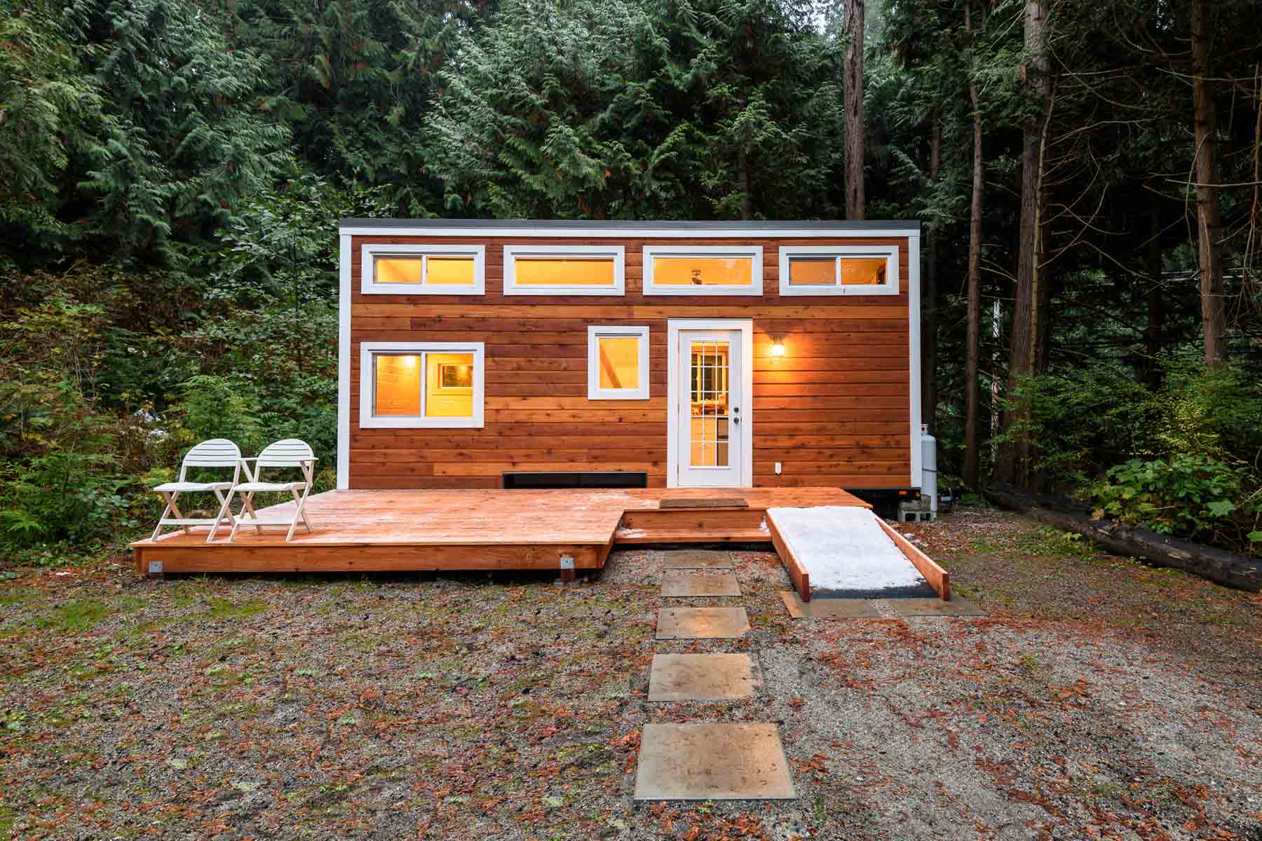 A tiny house on a foundation, with a wooden deck.