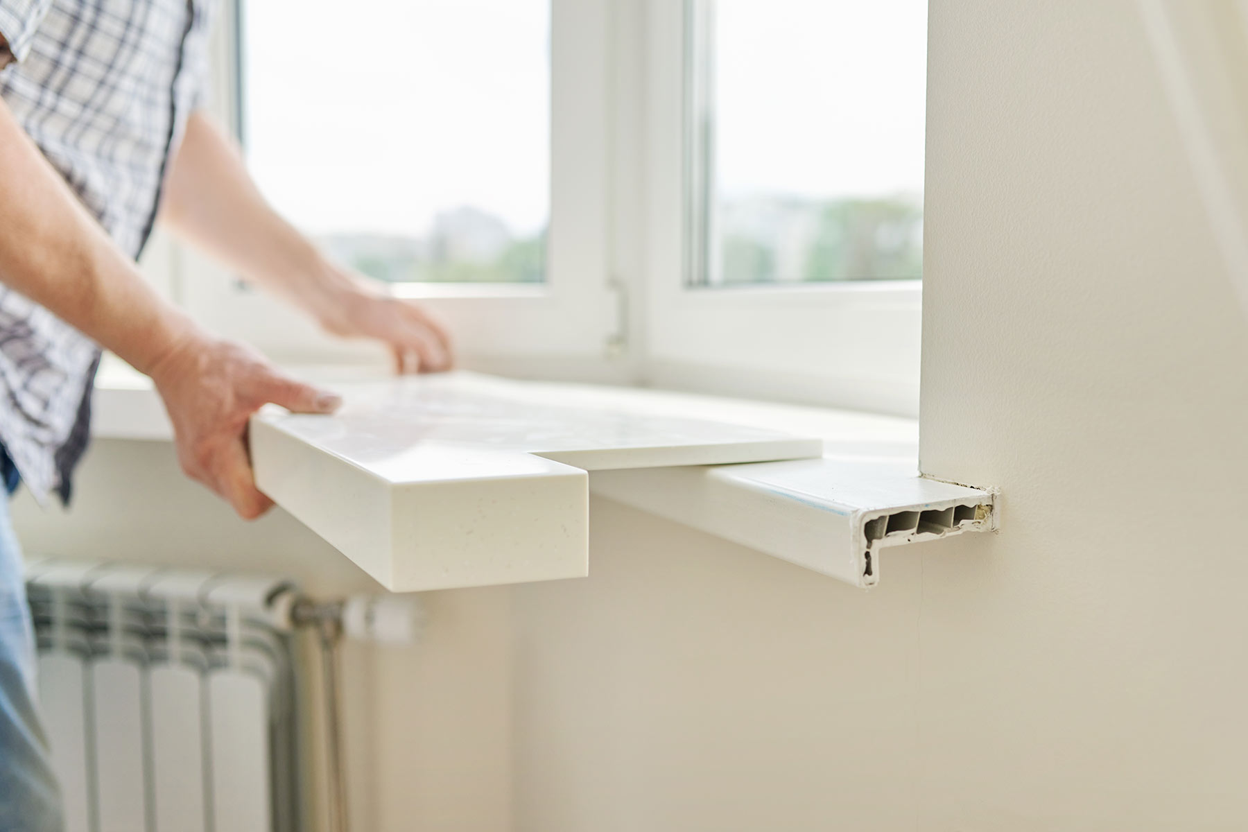 Worker installing an artificial stone window sill on a finished window frame
