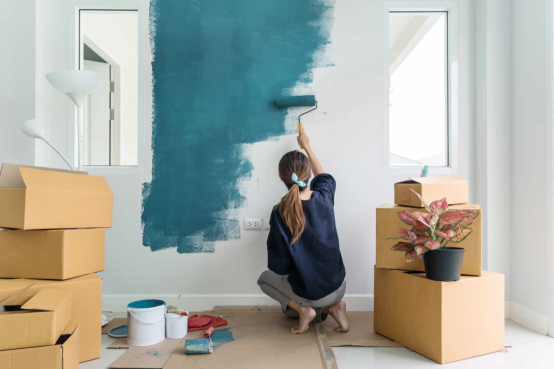 A woman painting an apartment interior wall with paint roller A woman painting an apartment interior wall with paint roller